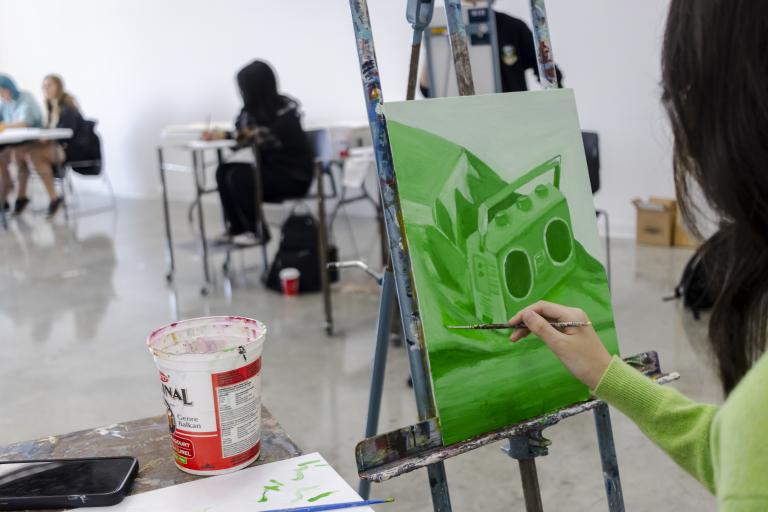 Teen painting student painting a green still life in a studio
