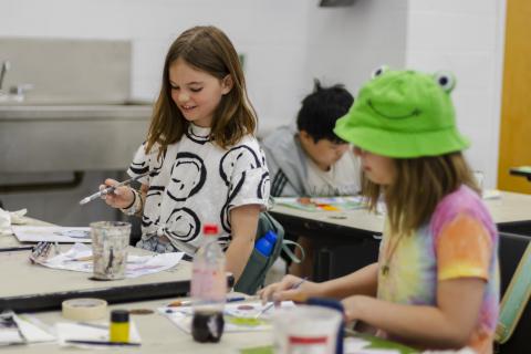 Two kids camp painting students work with their brushes smiling in a bright studio