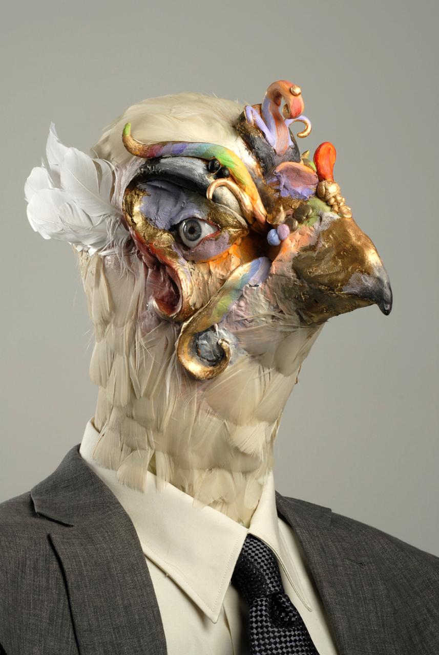 David Altemjd, 2007. Image depicts a zoomed in image of a sculpture. The sculpture is a creature wearing a suit. The head of this figure has been crafted to look like a white feathered bird. 