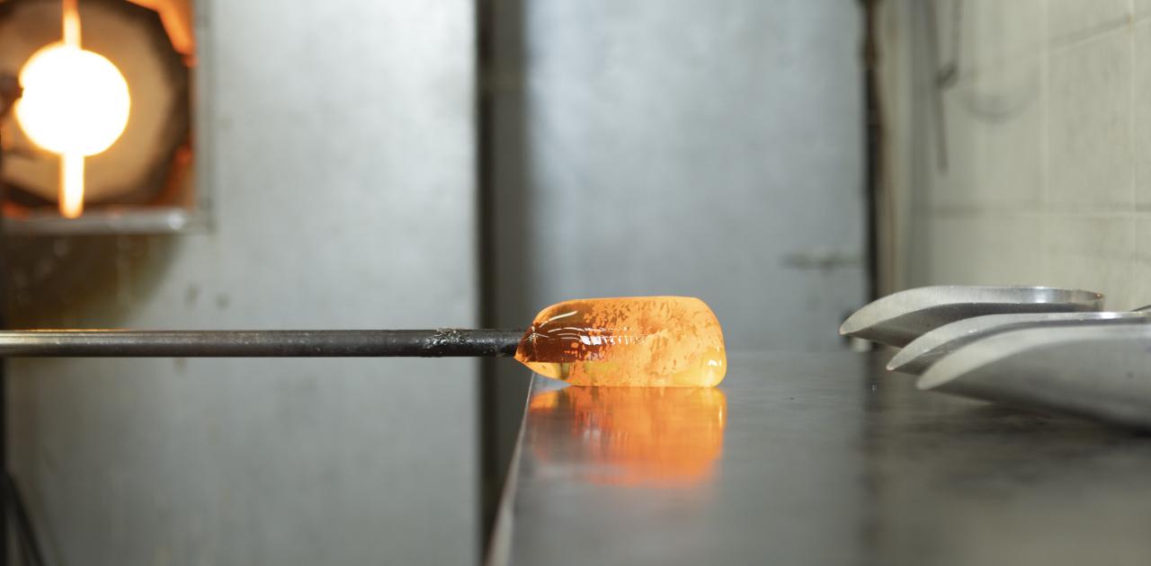Molten glass on a blowpipe glowing orange in the AUArts glass studio.