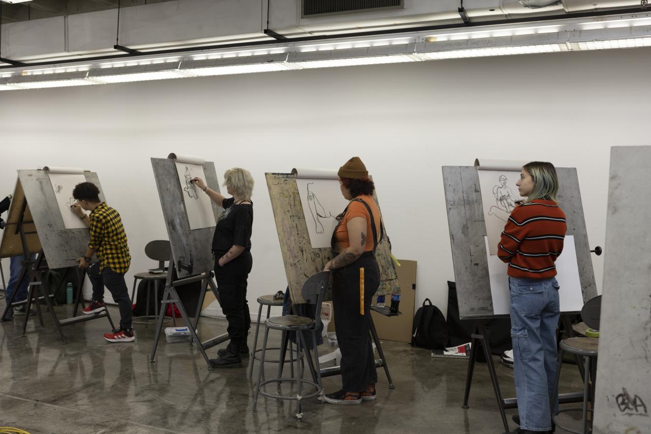 Drawing Community Students stand at easels sketching figure drawings in an AUArts classroom.