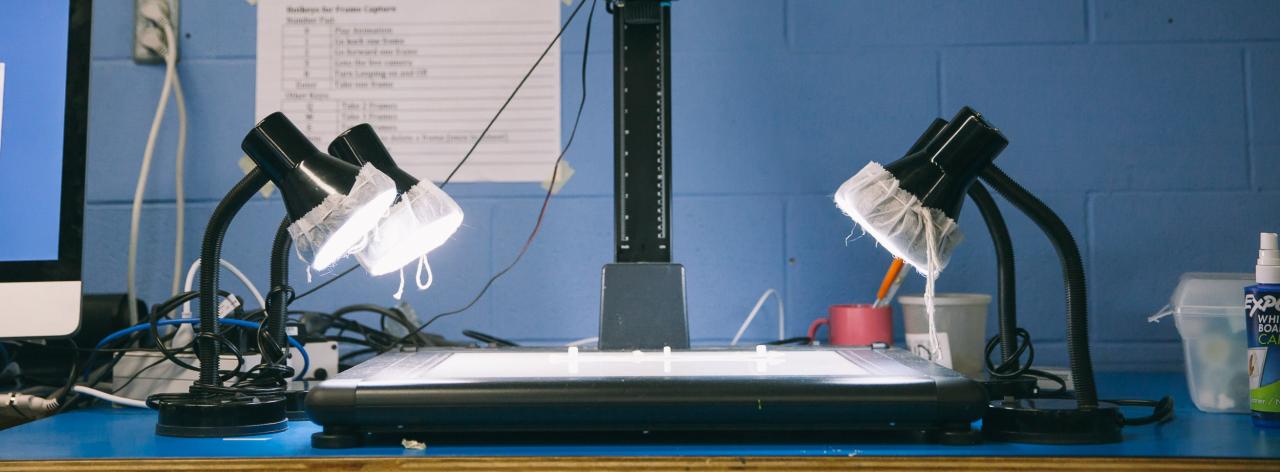 Animation workstation with a light table and four adjustable lamps, set up for frame-by-frame drawing and capture.