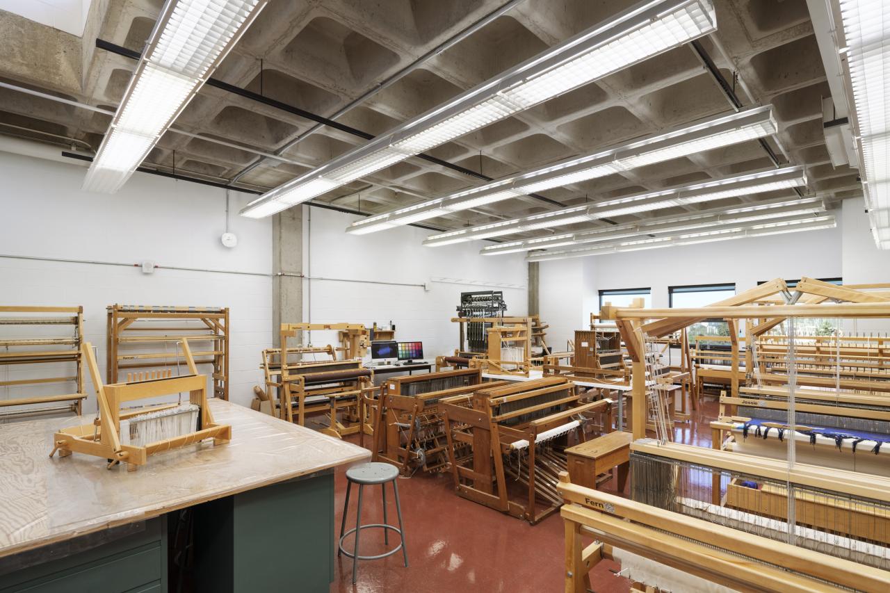 AUArts fibre studio with rows of wooden floor looms and weaving equipment in a bright, spacious classroom.
