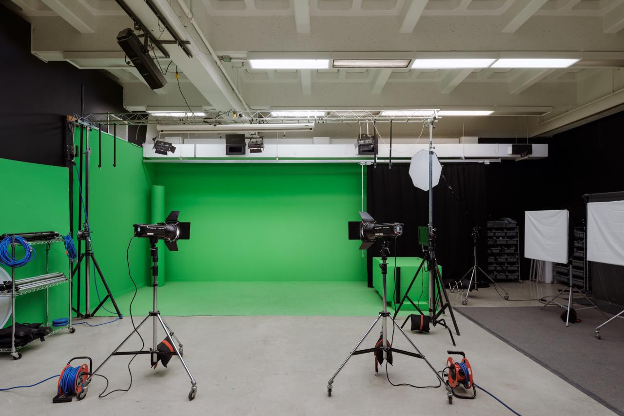 AUArts media studio with green screen backdrop, studio lighting, cables, and photography equipment.