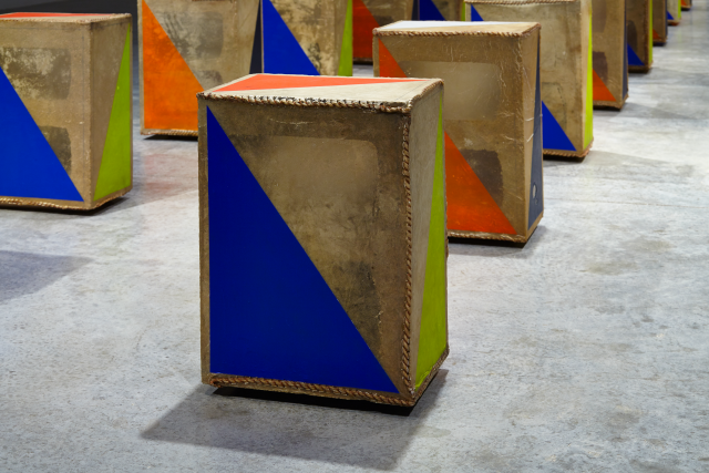 Detail of an object with blue, orange and green detail. The other objects are seen in the background. 
