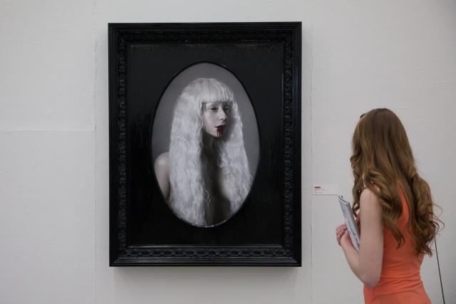 A guest standing to side of a black framed image. 