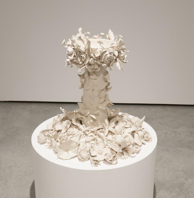 Detail Fountain 1 (2013). A beige unglazed fountain adorned in flowers sits a top a pedestal. 