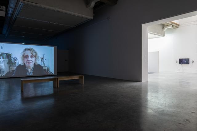 The Beyond Within video being shown in a darkened gallery with a bench