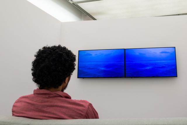 Man watching video from The Beyond Within showing blue waves