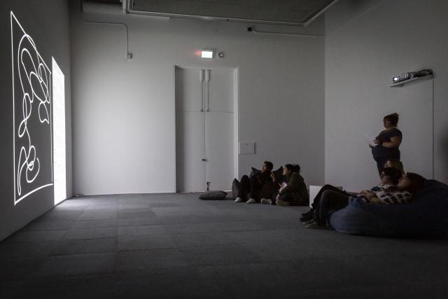 People watching a video installation from The Beyond Within while reclining in bean bag chairs