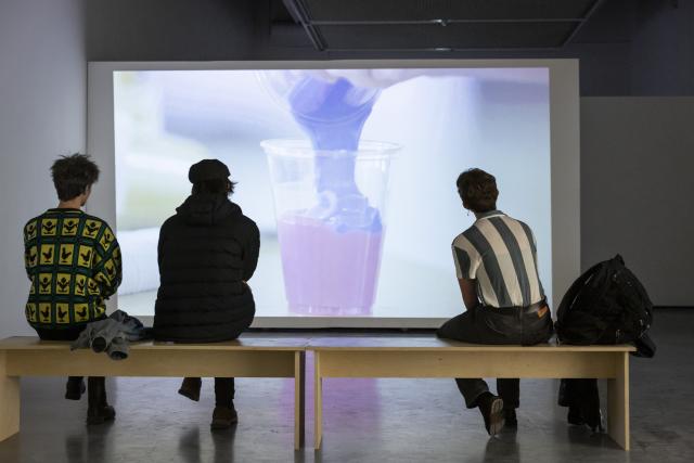 Three people watching a video installation from The Beyond Within