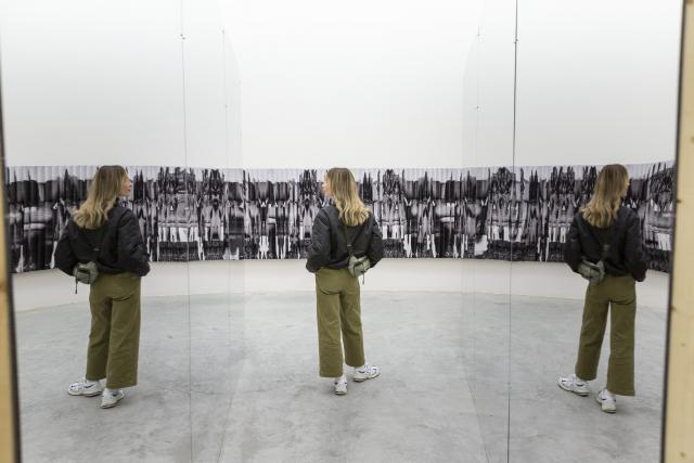 Person walking between two mirrors as their image is reflected back at them in a repeating pattern
