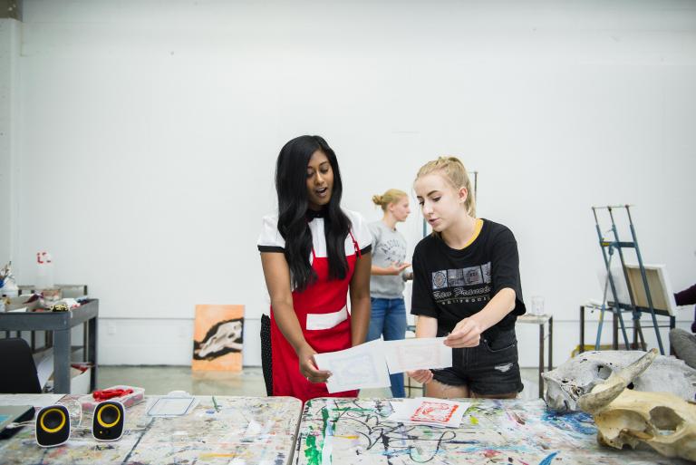 instructor gives student feedback in an art studio