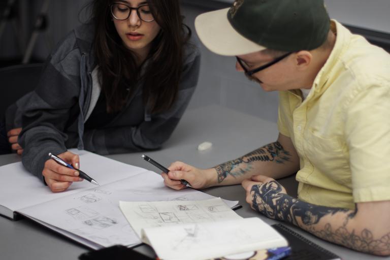 photograph of an art instructor helping a young student with a drawing