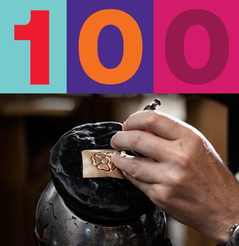 Close-up of a hand engraving a floral design on metal, with a bold '100' in colorful typography above, celebrating AUArts' centennial milestone.