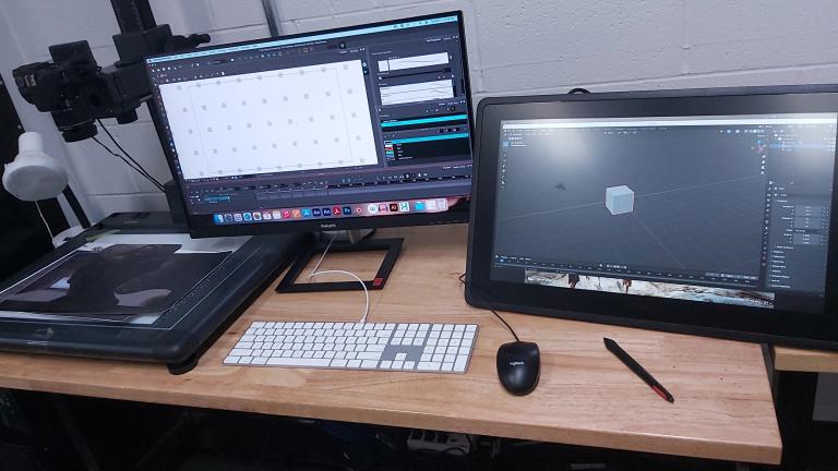 Animation Station A digital animation workstation with dual monitors, a drawing tablet, keyboard, and stylus, showing 3D modeling and animation software in use.